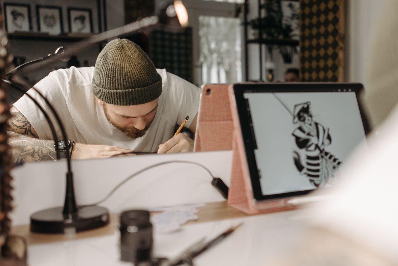 Artiste pleinement absorbé par le dessin sur un iPad, dans l’ambiance d’un studio contemporain.